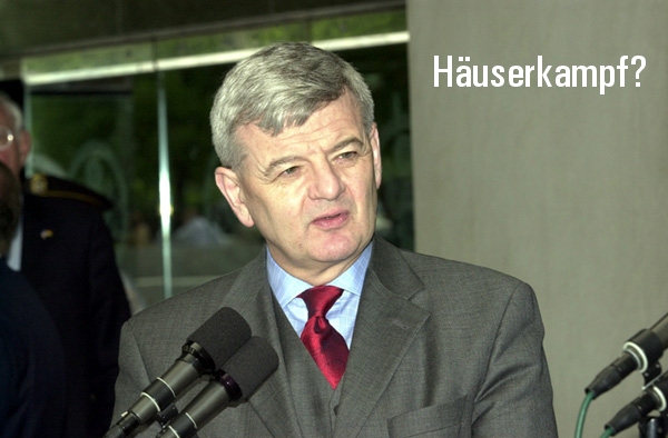 Außenminister Joschka Fischer auf einer Pressekonferenz. Hinzugefügter Text: 'Häuserkampf?'